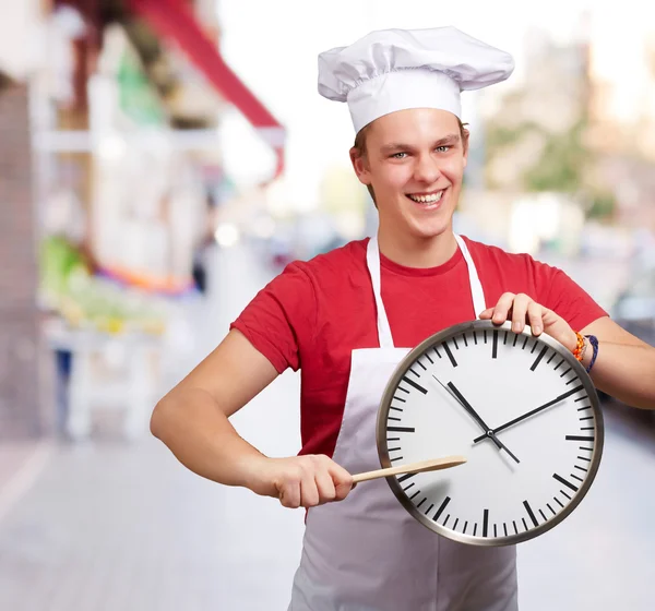Retrato del joven cocinero apuntando un reloj a la calle —  Fotos de Stock