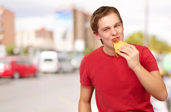 Portrait of young man eating pizza at street — Stock Photo, Image