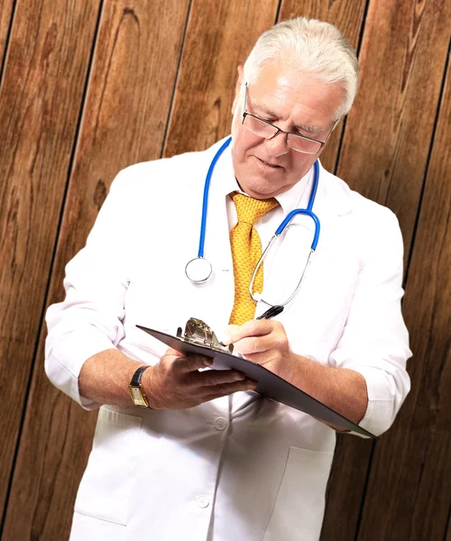 Senior mannelijke arts schrijven op Klembord — Stockfoto
