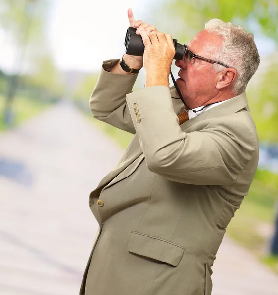 Homem sênior olhando através de binóculos — Fotografia de Stock