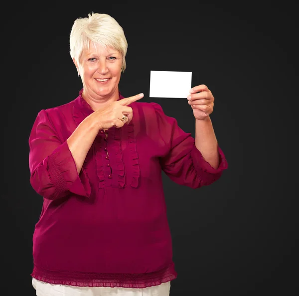 Retrato de uma mulher sênior apontando para o cartão em branco — Fotografia de Stock