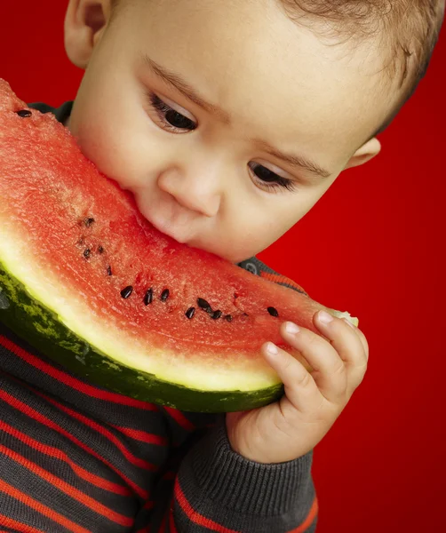Miúdo bonito degustando uma melancia — Fotografia de Stock