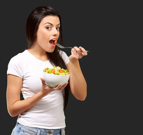 Молода дівчина їсть салат з миски — стокове фото