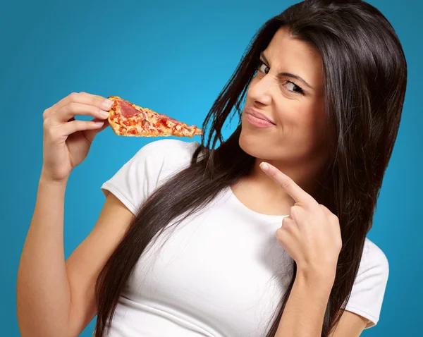 Portret van een jonge vrouw die een stuk van pizza eten — Stockfoto