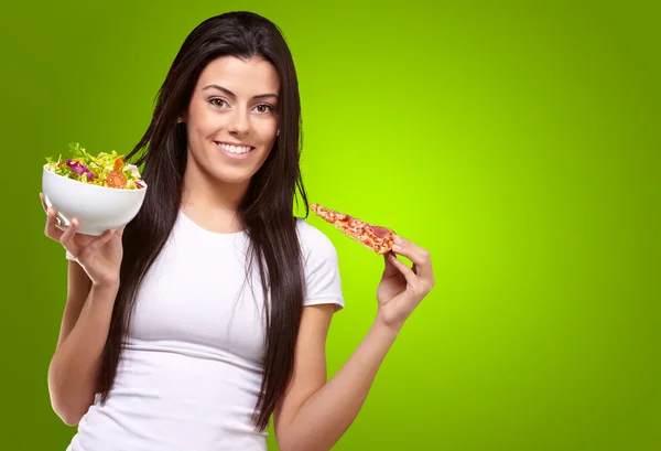 Kvinna håller en bit pizza och sallad skål — Stockfoto