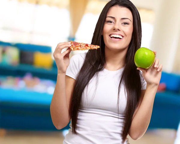 Mujer sosteniendo un pedazo de pizza y una manzana — Foto de Stock