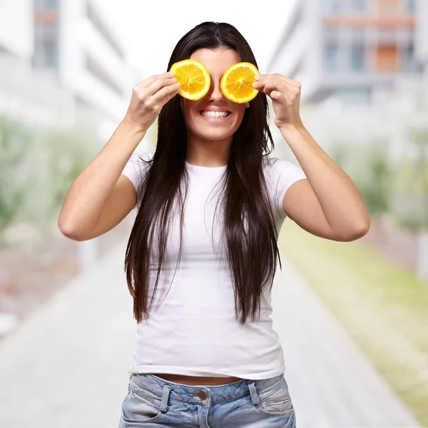 彼女の ey の前にオレンジ スライスを保持している若い女性の肖像画 — ストック写真