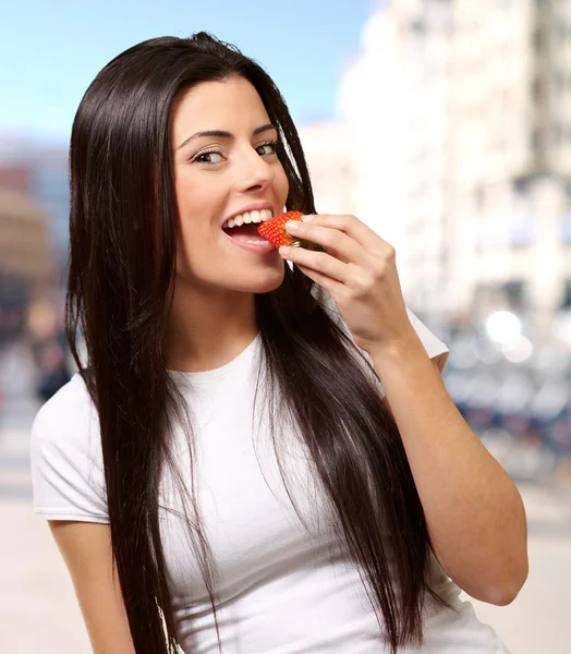 都市でイチゴを食べる若い女性の肖像画 — ストック写真