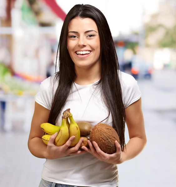 Portrait of young woman holding tropical fruits at street — Stock Photo, Image