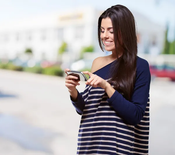 Портрет молодой женщины, трогающей современный мобильный телефон на улице — стоковое фото