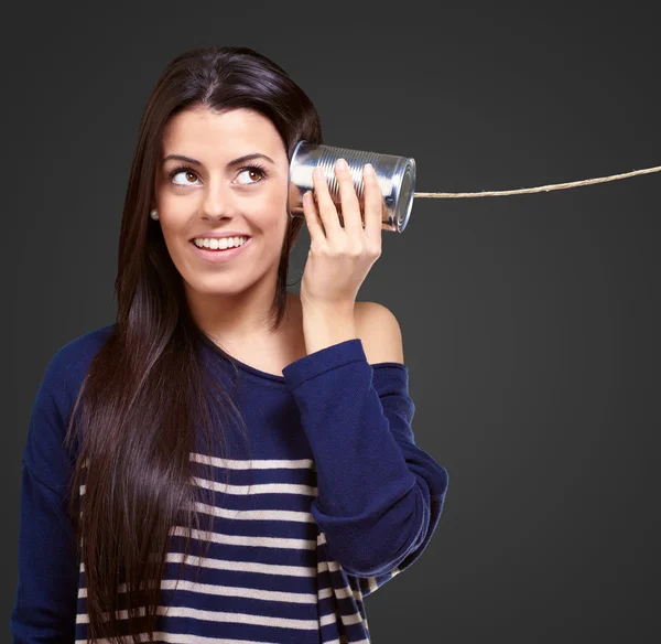 Mujer sosteniendo una lata de metal como un teléfono — Foto de Stock