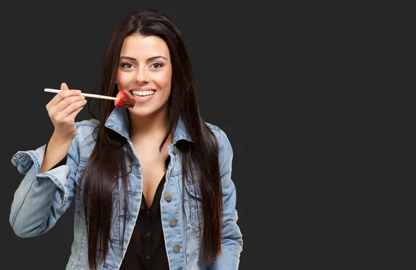 Retrato de uma fêmea comendo morango com molho de chocolate — Fotografia de Stock