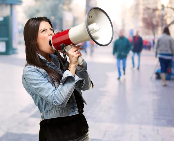 Retrato de mujer joven gritando con megáfono en el brillo lleno de gente — Foto de Stock