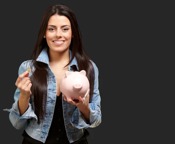 Portret van een vrouw holding een munt en spaarpot — Stockfoto