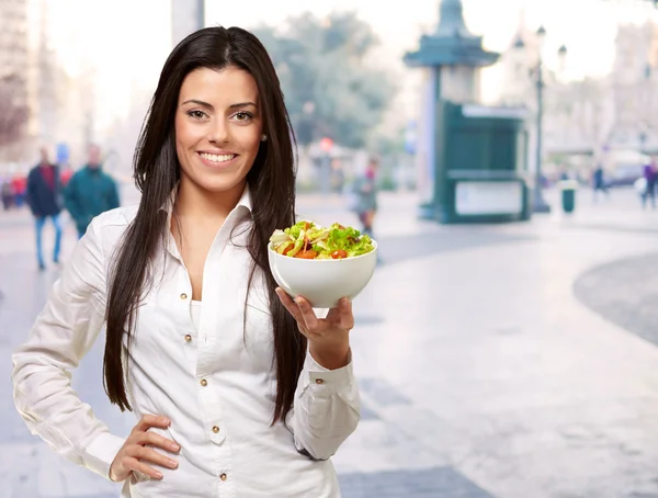 Портрет молодой женщины, держащей салат на улице — стоковое фото