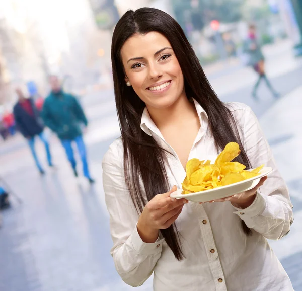 Portrait d'une jeune femme tenant une assiette de chips de pommes de terre en ville — Photo