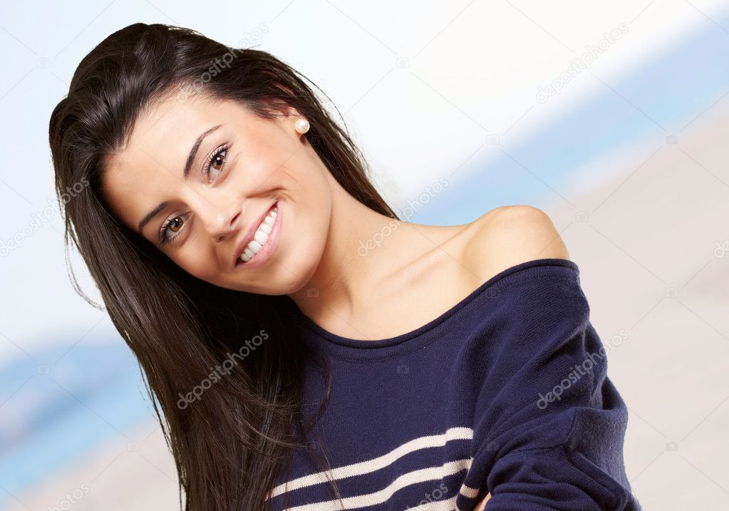 Portrait of young woman smiling against a beach