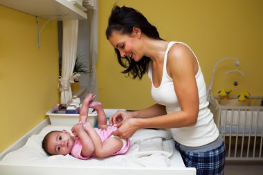 A mother changing her baby nappy . clipart