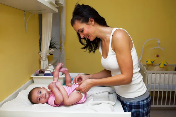 Una madre cambiando su pañal de bebé  . Imagen de stock