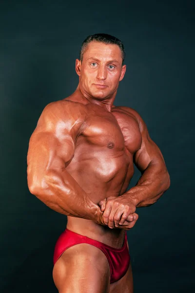 Bodybuilder posiert auf dunklem Hintergrund. — Stockfoto