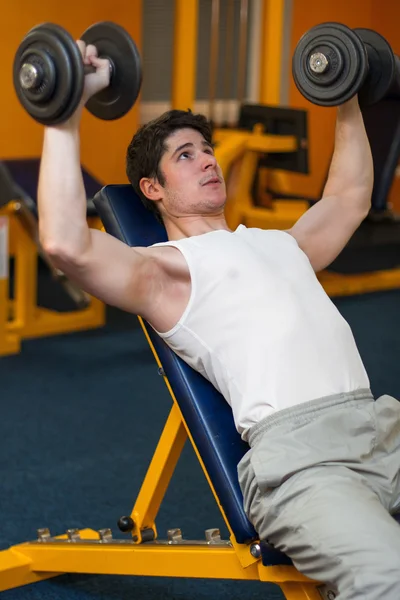 Young man lifting dumbbells in sport club — Stock Photo, Image
