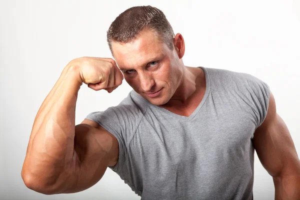 Muskulöser Mann, der seinen Bizeps auf weiß anlegt — Stockfoto