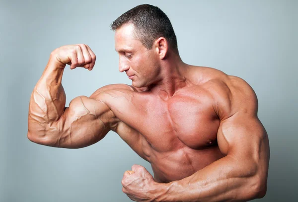 Muskulöser Mann, der seinen Bizeps beugt — Stockfoto