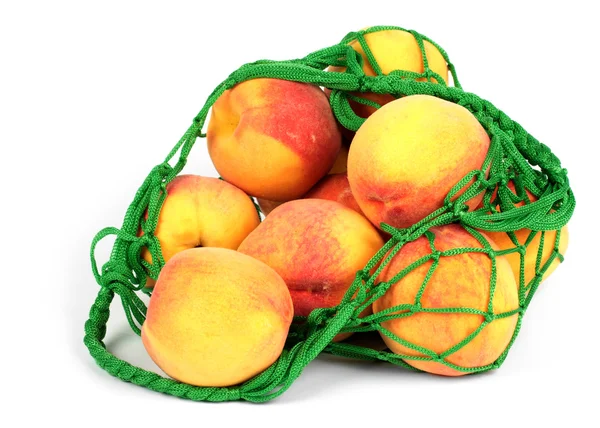The peaches in a green string bag — Stock Photo, Image