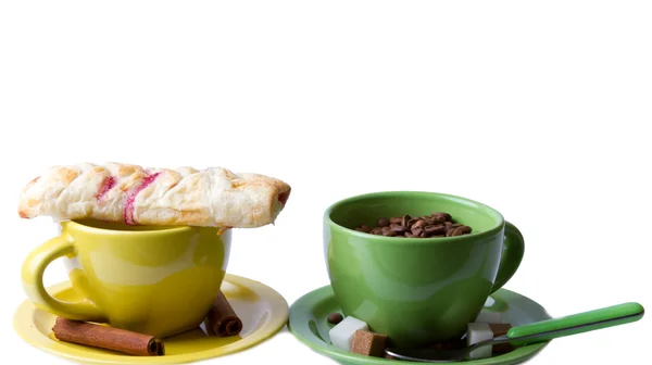 Grüne und gelbe Tassen mit Muffin und Kaffeebohnen — Stockfoto