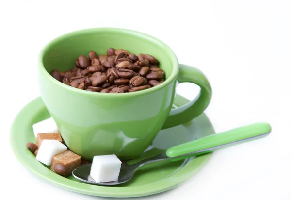 A xícara verde com uma colher com grãos de café e pedaços de açúcar — Fotografia de Stock