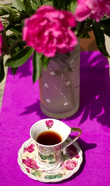 Xícara de chá no fundo de um buquê de peônias — Fotografia de Stock