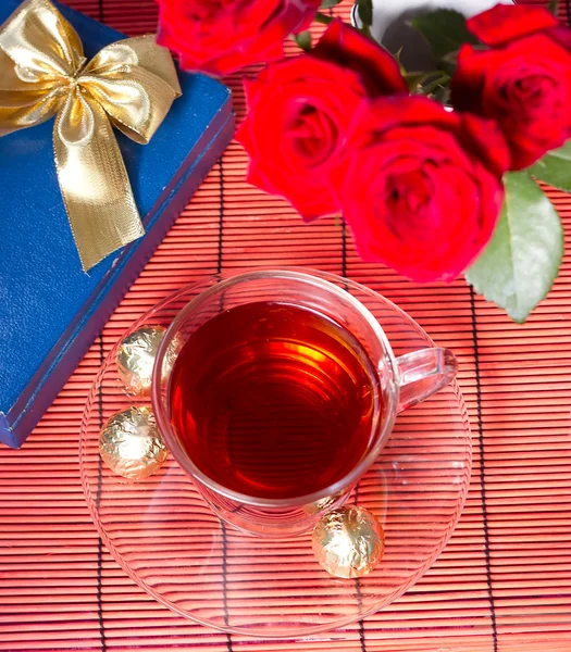 Herbata i słodycze obok bukiet róż — Zdjęcie stockowe