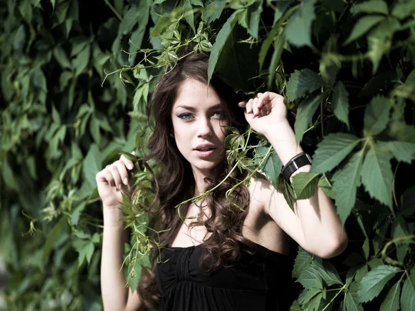 Meisje op een achtergrond van groene bladeren — Stockfoto