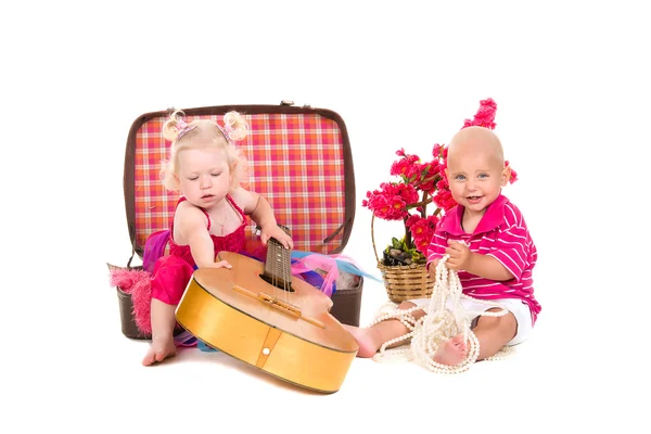 Мальчик и девочка играют возле чемодана, гитара — стоковое фото