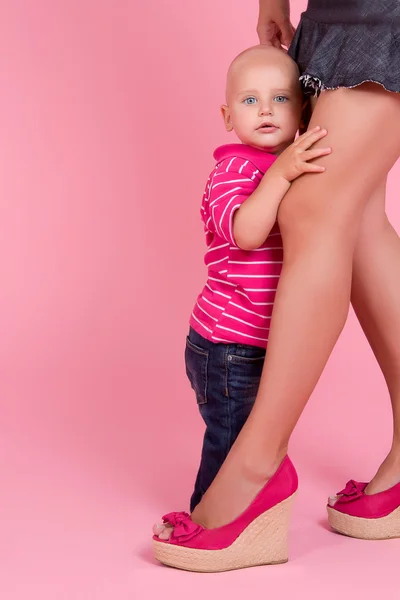 Мальчик прячется за мамиными ногами — стоковое фото