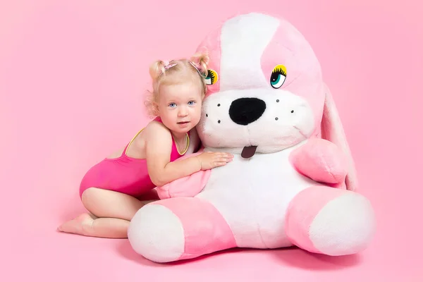 Girl in a pink bathing suit hugging a stuffed toy — Stock Photo, Image