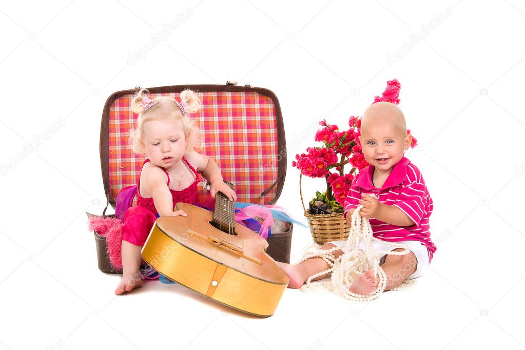 Boy and girl playing near a suitcase, a guitar
