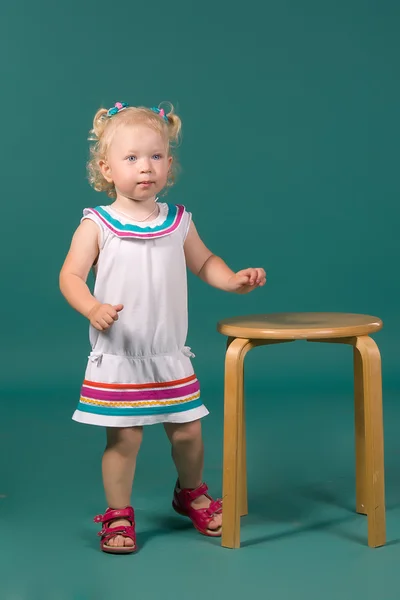 Κορίτσι σε λευκό φόρεμα στέκεται κοντά σε μια καρέκλα — Φωτογραφία Αρχείου