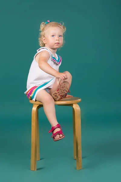 Menina de vestido branco sentado em uma cadeira — Fotografia de Stock