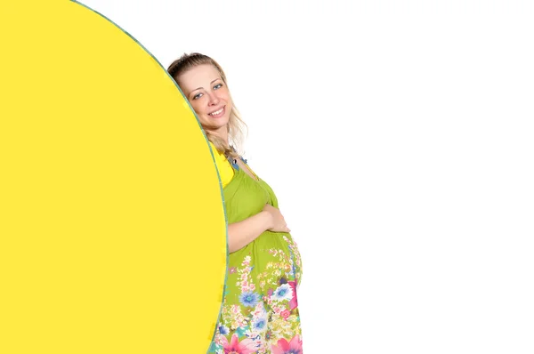 Pregnant woman looks out a yellow fan — Stock Photo, Image