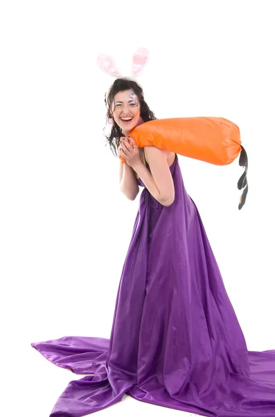Девушка в шелковом платье, с кроличьими ушами и морковью в руке — стоковое фото