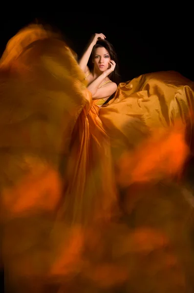Meisje in de oranje jurk van vliegen stof — Stockfoto
