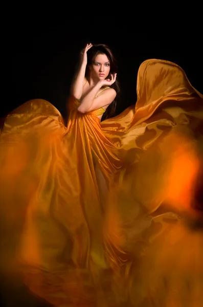 Menina no vestido laranja de tecido voador Fotografia De Stock