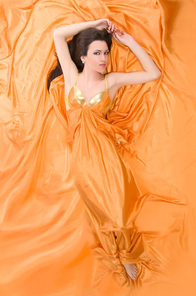 Girl lying on orange satin — Stock Photo, Image