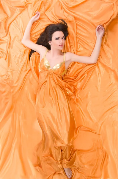 Dívka ležela na oranžové saténové — Stock fotografie