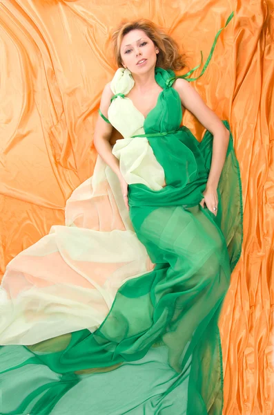 L blonde in the yellow and green silk fabrics — Stock Photo, Image