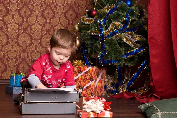 Menino imprime carta ao Papai Noel em uma máquina de escrever — Fotografia de Stock