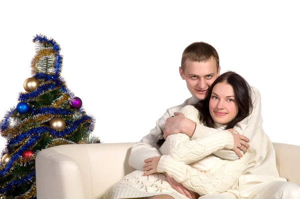 Ζευγάρι στο χριστουγεννιάτικο δέντρο δίπλα σε ένα λευκό καναπέ — Φωτογραφία Αρχείου