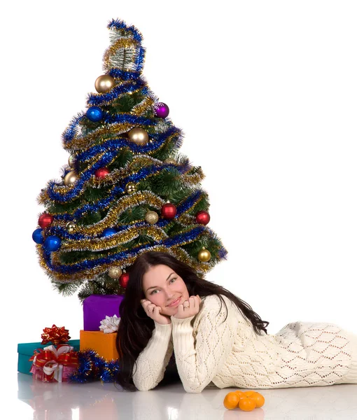 Schönes Mädchen, das neben einem angekleideten Weihnachtsbaum liegt — Stockfoto