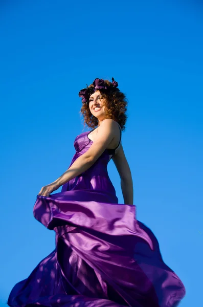 紫色のドレスを飛んでいる巻き毛の女の子 — ストック写真